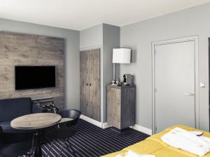 a hotel room with a bed and a table and a tv at Mercure Nancy Centre Place Stanislas in Nancy