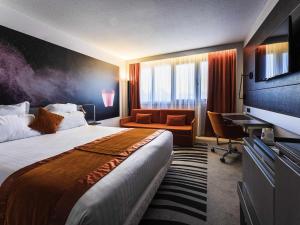 a hotel room with a large bed and a desk at Novotel Orléans Saint Jean de Braye in Saint-Jean-de-Braye