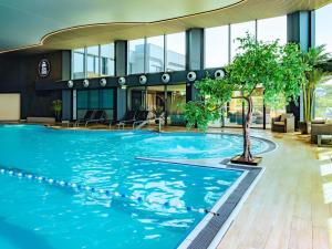 a pool in a building with a tree in the middle at Côte Ouest Thalasso & Spa Les Sables d'Olonne - MGallery Collection in Les Sables-dʼOlonne