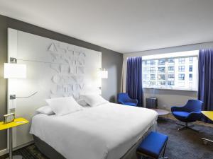 a hotel room with a large bed and blue chairs at Mercure Rennes Centre Parlement in Rennes