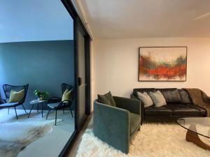 Una sala de estar con un sofá, una mesa y sillas. en Urban Retreat - Shared Apartment with Queen Bed and Private Ensuite, en Brisbane