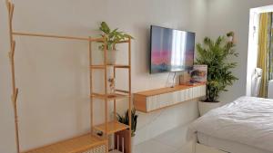 a bedroom with a tv on a wall with plants at Serene Haven with Skyline View in Sampong