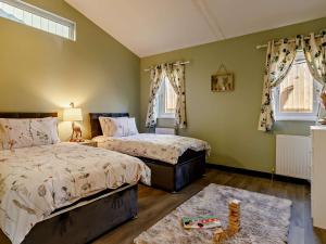 two beds in a bedroom with green walls and windows at 2 Bed in Sidmouth 91118 in Ottery Saint Mary