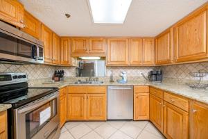 Una cocina con gabinetes de madera y electrodomésticos de acero inoxidable. en Phoenix VII 7503 condo, en Orange Beach