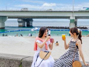 two women sitting on the beach drinking drinks at Nishitetsu Resort Inn Naha in Naha
