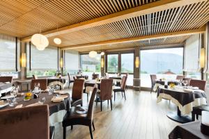 un restaurante con mesas, sillas y ventanas grandes en La Croix de Savoie & Spa, en Les Carroz d'Araches
