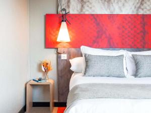 een slaapkamer met een groot bed en een rood schilderij bij Hôtel Ibis Cognac Centre in Cognac