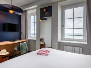 a room with a bed and a desk and windows at ibis Saint Malo Plage in Saint Malo +110 photos