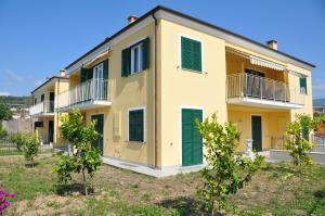 a large yellow building with green shutters at Villaggio La Piana in Cervo