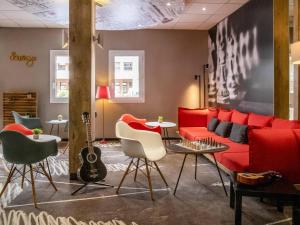 a living room with a red couch and a guitar at ibis Gap Centre in Gap