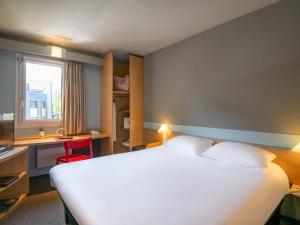 a hotel room with a large white bed and a desk at ibis Gap Centre in Gap