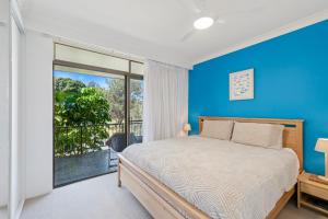 Un dormitorio con una cama y una pared azul. en Hawaiian Gardens 2, en Coffs Harbour