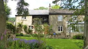 una antigua casa de piedra con un jardín delante de ella en Chinley End Farm, en Chinley