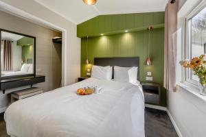 a bedroom with a large white bed with a green wall at Marina Retreat in Carlton Colville