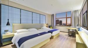 a bedroom with two beds and a large window at Echarm Hotel Changchun Yiqi Automotive Trade City Wanda in Changchun +172 photos
