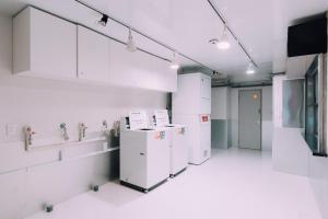 大阪市にあるMinimalist Loft 2 Namba Compact Studio and 24 hours Gym 05の白い家電製品、シンク、テレビが備わる客室です。