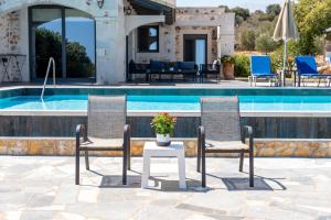 two chairs and a table next to a swimming pool at Villa Resi in Vamos
