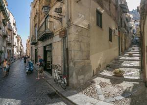 a man standing next to a building with a bike on a street at Caracciolo Lounge in Cefalù