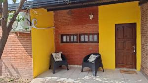 two chairs in front of a building with a door at Complejo Los Azahares in Roque Sáenz Peña