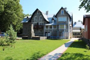 a large gray house with a grass yard at Apartamentai Vanagupės rajone in Palanga