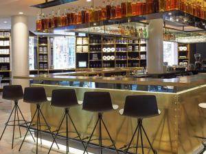 a bar with black stools in front of a counter at INK Hotel Amsterdam - MGallery Collection in Amsterdam