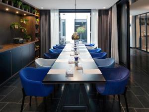 a long dining room with a long table and blue chairs at INK Hotel Amsterdam - MGallery Collection in Amsterdam