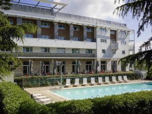 a hotel with a swimming pool in front of a building at Novotel Saint-Quentin en Yvelines in Magny-les-Hameaux