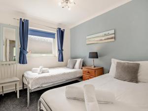 a bedroom with two beds and a window with blue curtains at 2 Bed in Brixham BX079 in Brixham +16 photos