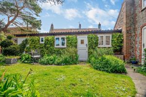 une maison en briques avec une porte blanche et une cour dans l'établissement Bourne Cottage, à Weybourne