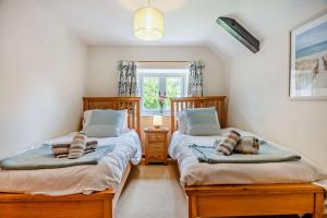 deux lits jumeaux dans une chambre avec fenêtre dans l'établissement Bourne Cottage, à Weybourne