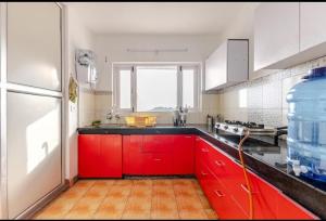 a kitchen with red cabinets and a refrigerator at The sunrise Himalayas view cottage in Bhowāli +39 photos