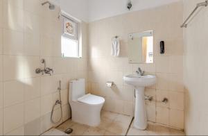a white bathroom with a toilet and a sink at The sunrise Himalayas view cottage in Bhowāli