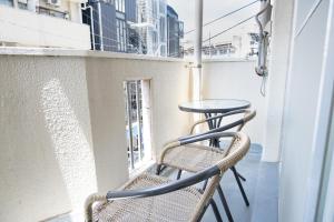 un balcon avec deux chaises et une table dans l'établissement Fukuoka Hakata Stay 1BR with Balcony, TV and Laundry, à Fukuoka