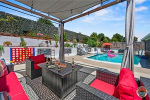 eine Terrasse mit roten Stühlen, einem Tisch und einem Pool in der Unterkunft Relax and Unwind 4BR La Mesa Home with Pool plus Spa in La Mesa
