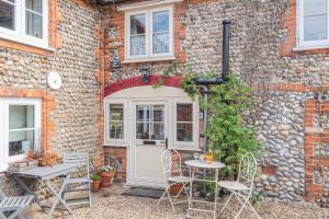 a patio with a table and chairs in front of a building at White Rose Cottage in Bodham