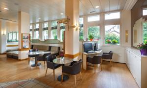 a waiting room with tables and chairs and a television at Hotel Welcome Inn in Kloten