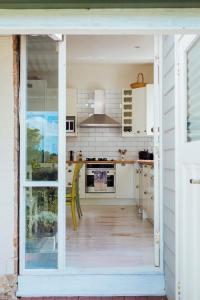 a kitchen with white cabinets and an open door at Illalangi Boutique Cottage in Blackheath