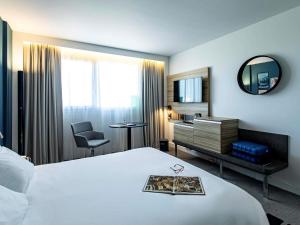 a hotel room with a bed and a mirror at Novotel Beaune in Beaune