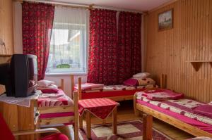 ムシャナ・ドルナにあるOśrodek wypoczynkowy "Jak u Mamy"のベッド3台、窓(赤いカーテン付)が備わる客室です。