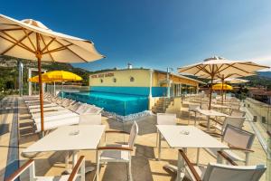 un patio con mesas y sombrillas y una piscina en Sky Pool Hotel Sole Garda, en Garda