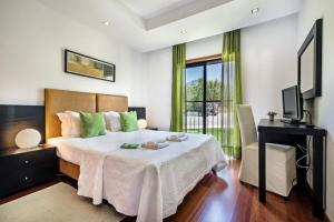 a bedroom with a bed and a desk and a television at Baia da Luz Resort in Luz +37 photos