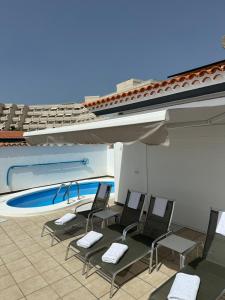 a group of chairs sitting next to a swimming pool at Villa Alexander in Puerto de Santiago