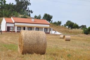 a field with hay bales in front of a house at Monte do Espadanal in Cercal