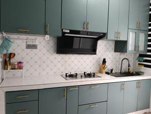 a kitchen with green cabinets and a sink at Homestay impian, arau in Arau