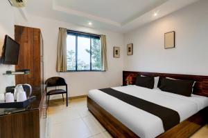 a bedroom with a bed and a chair and a television at Super Townhouse Nagpur Airport Formerly Flora Inn in Dhantoli