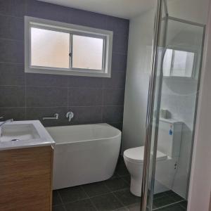 łazienka z wanną, toaletą i umywalką w obiekcie Wenlaw Cottage Rear Hat Head - Bring your own linen. w mieście Hat Head +8 zdjęć