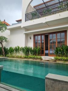 a villa with a swimming pool in front of a house at Agusta Villas in Uluwatu
