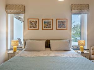 a bedroom with a bed with two windows and two lamps at 1 Bed in High Bickington 55322 in High Bickington