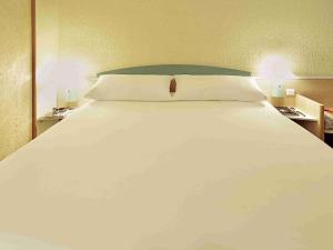 ein großes weißes Bett in einem Schlafzimmer mit zwei Lampen in der Unterkunft ibis Marseille Timone in Marseille