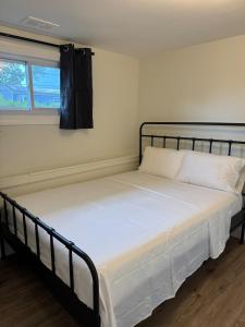 a bedroom with a bed with white sheets and a window at Comfort Stay by Stony Brook University & Hospital in Centereach